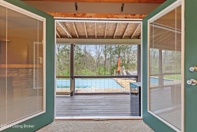 doorway featuring beamed ceiling and carpet flooring