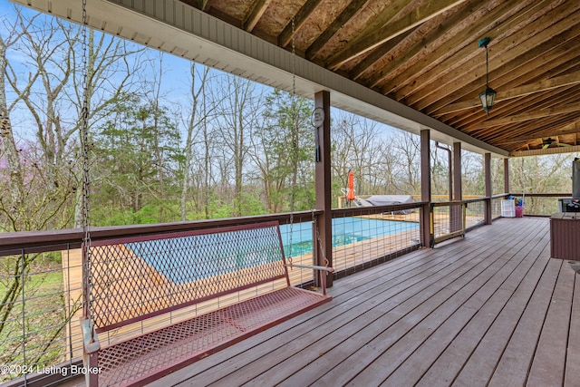 deck featuring ceiling fan and a covered pool