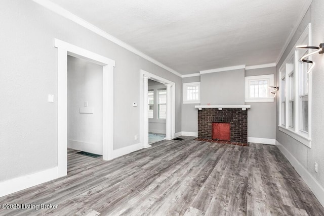 unfurnished living room featuring ornamental molding, a fireplace, and wood finished floors