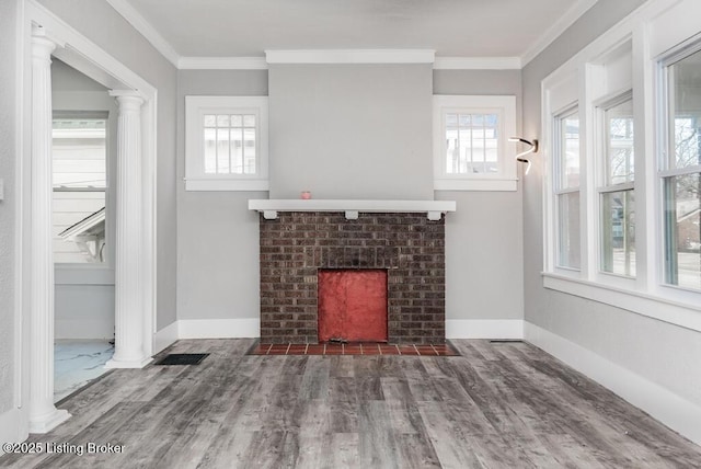 unfurnished living room with decorative columns, a fireplace, ornamental molding, and wood finished floors