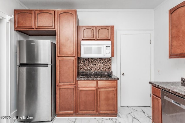 kitchen featuring marble finish floor, stainless steel appliances, decorative backsplash, brown cabinetry, and dark stone counters