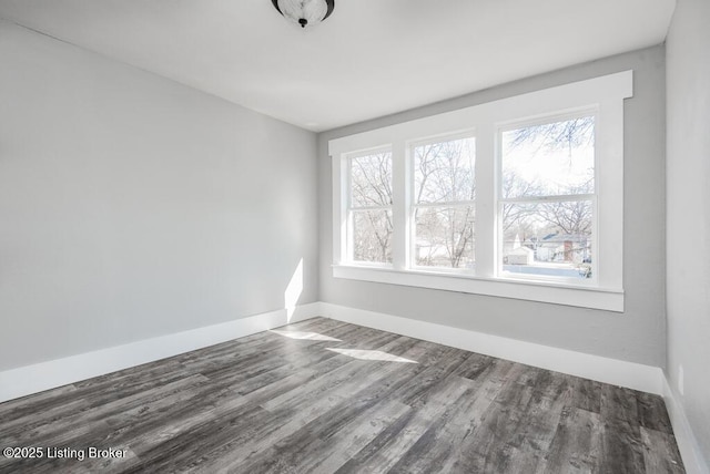 unfurnished room featuring a wealth of natural light, baseboards, and wood finished floors