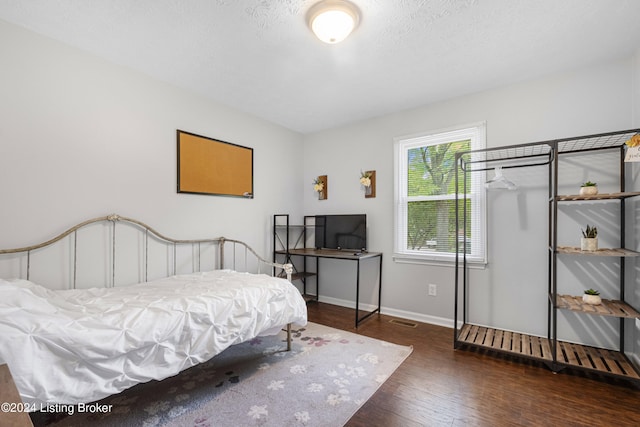 bedroom with a textured ceiling and dark hardwood / wood-style flooring