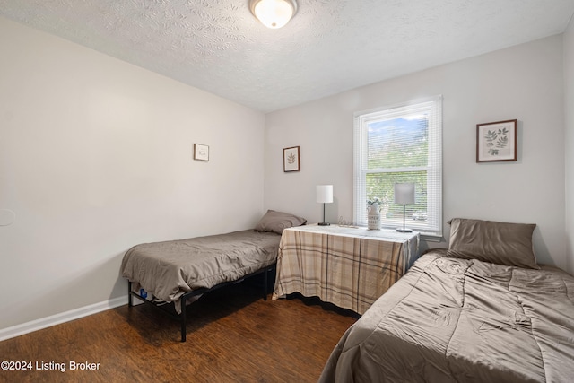 bedroom with a textured ceiling and dark hardwood / wood-style flooring