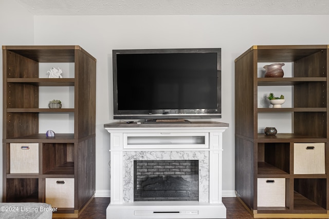 unfurnished living room featuring a premium fireplace, a textured ceiling, and dark hardwood / wood-style floors