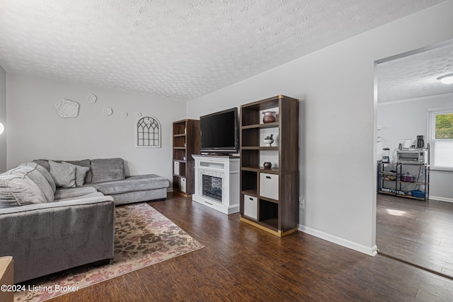 living room featuring dark wood-type flooring and a textured ceiling