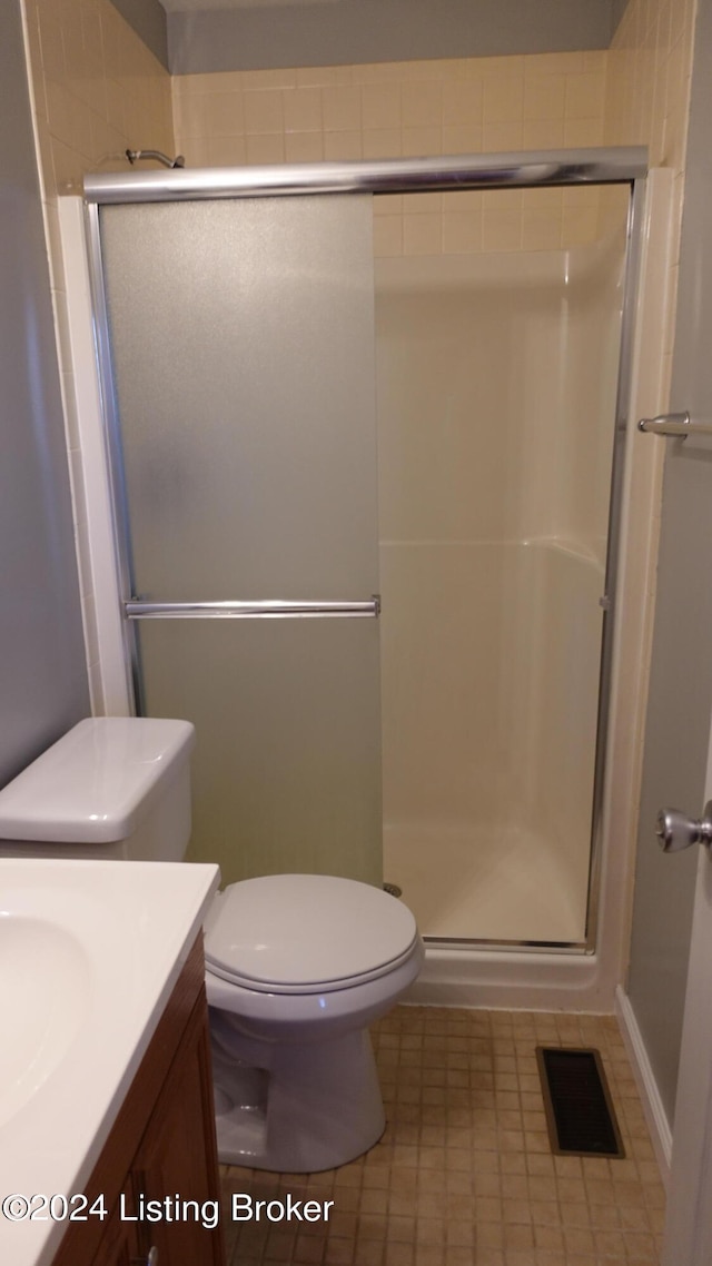 bathroom with vanity, an enclosed shower, toilet, and tile patterned floors