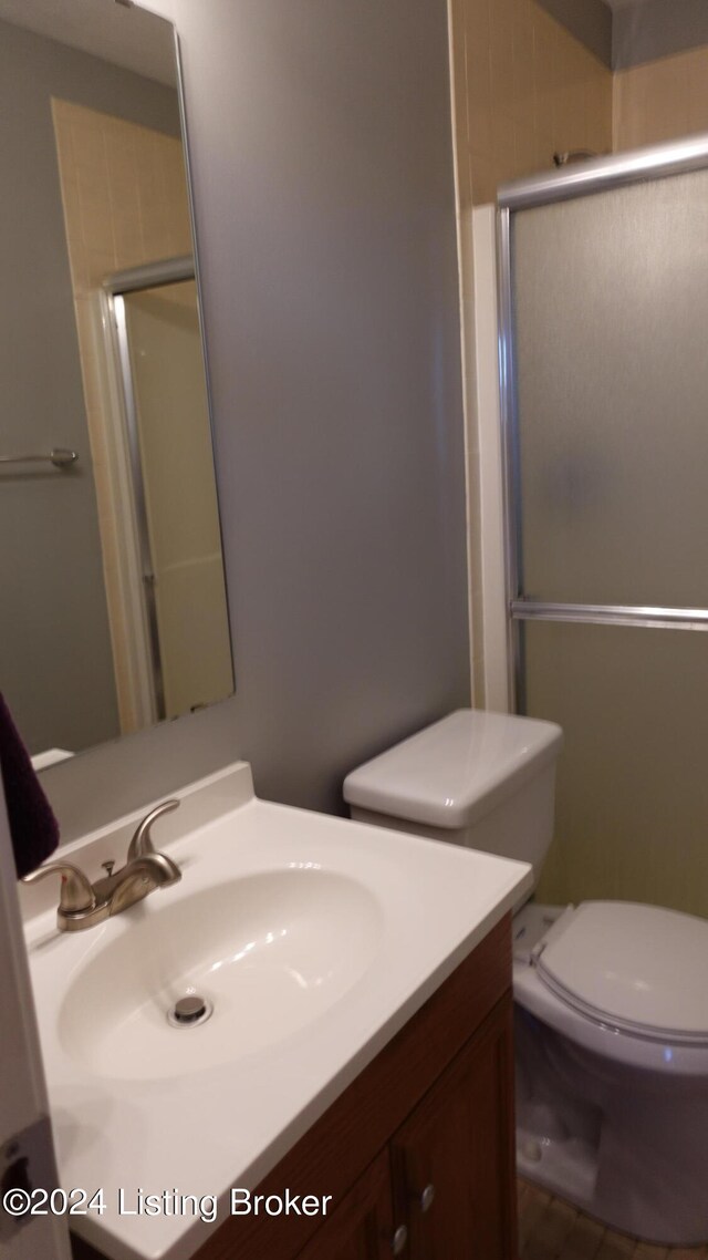 bathroom featuring vanity, toilet, a shower with shower door, and tile patterned flooring