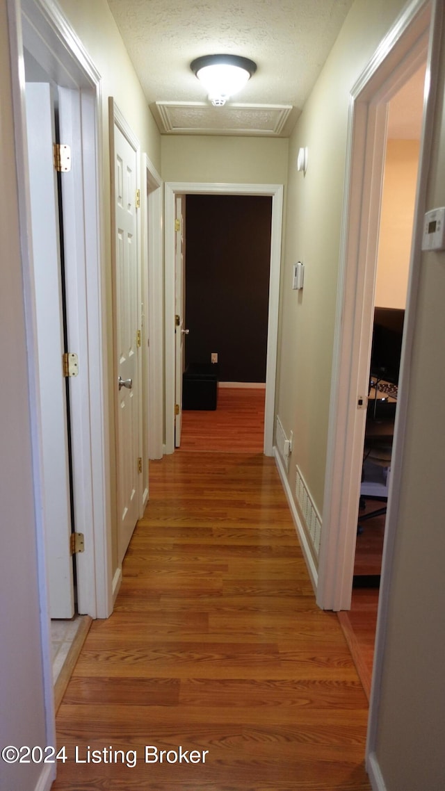 hall with a textured ceiling and hardwood / wood-style floors