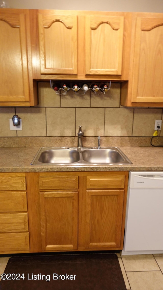 kitchen with light tile patterned flooring, tasteful backsplash, sink, and white dishwasher