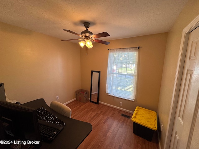 interior space featuring ceiling fan, wood-type flooring, and a textured ceiling