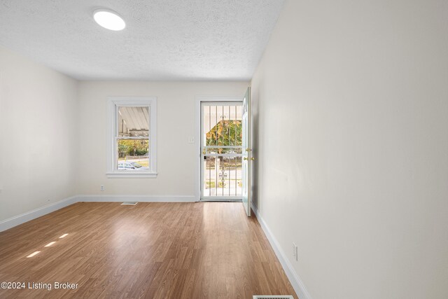 unfurnished room with a textured ceiling and hardwood / wood-style flooring