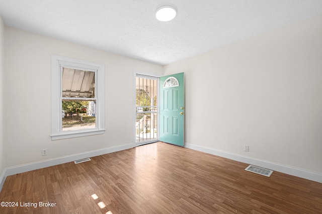 unfurnished room featuring a textured ceiling and hardwood / wood-style floors