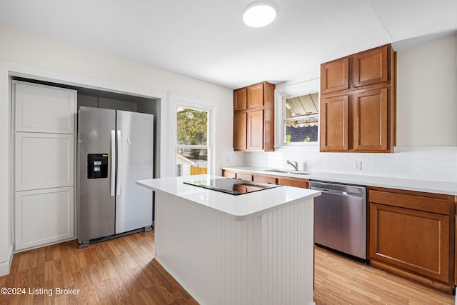 kitchen featuring decorative backsplash, a center island, stainless steel appliances, and light wood-type flooring