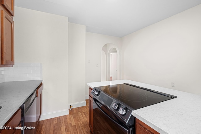 kitchen with stainless steel dishwasher, black electric range, decorative backsplash, and light hardwood / wood-style floors