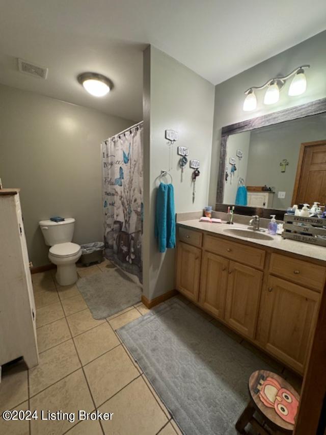 bathroom featuring visible vents, toilet, vanity, tile patterned flooring, and baseboards