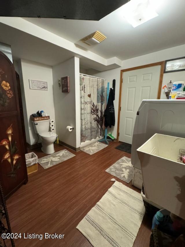 bathroom with hardwood / wood-style flooring, toilet, and walk in shower