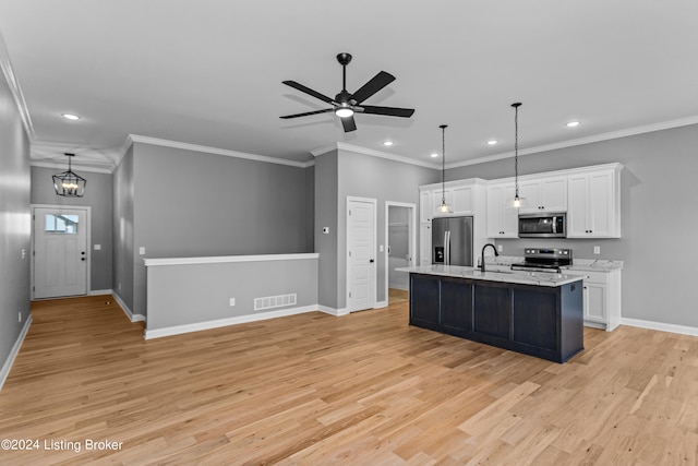 kitchen with hanging light fixtures, an island with sink, white cabinetry, light hardwood / wood-style flooring, and stainless steel appliances