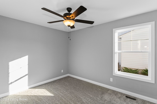 carpeted spare room featuring a wealth of natural light and ceiling fan