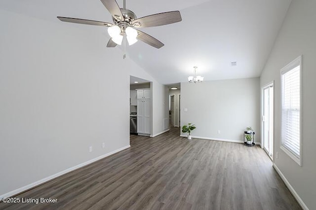 unfurnished living room with ceiling fan with notable chandelier, high vaulted ceiling, and dark hardwood / wood-style flooring