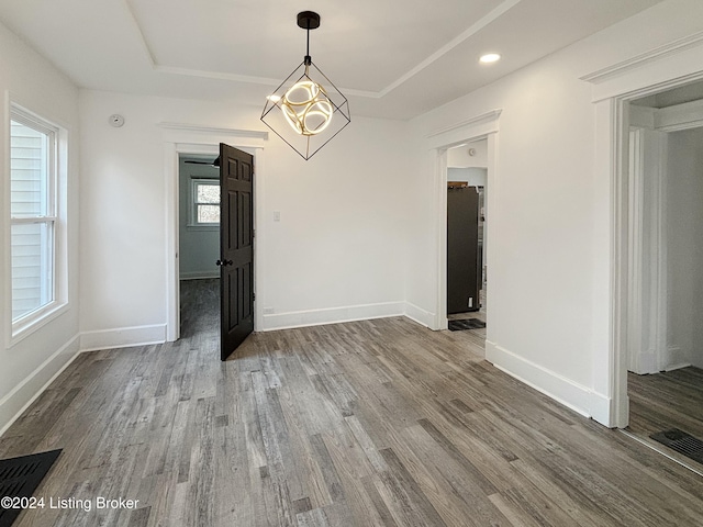 unfurnished dining area featuring hardwood / wood-style flooring, plenty of natural light, and a raised ceiling