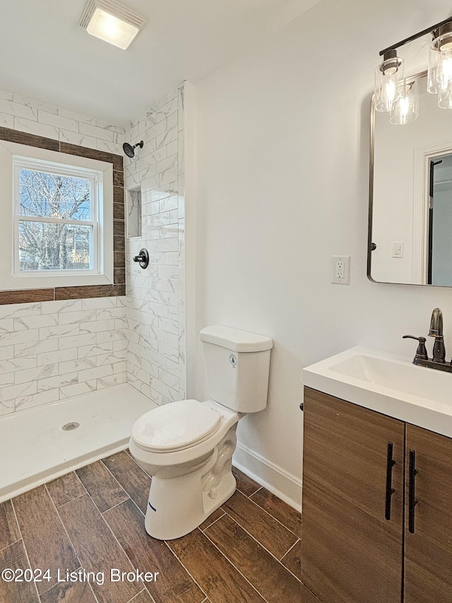 bathroom with toilet, vanity, and tiled shower