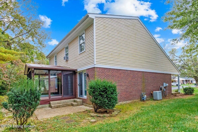 view of home's exterior featuring cooling unit, a yard, and a sunroom