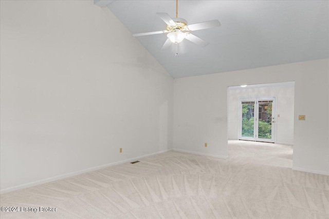 empty room featuring ceiling fan, vaulted ceiling, and light colored carpet