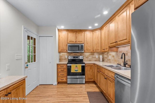 kitchen featuring sink, light hardwood / wood-style flooring, stainless steel appliances, and backsplash