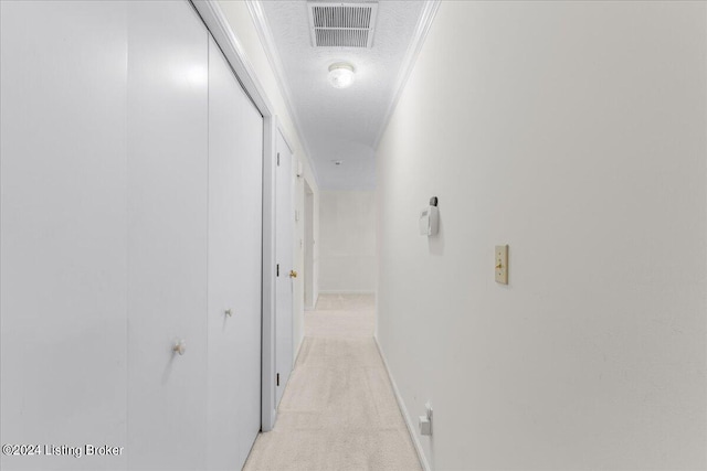 hall featuring ornamental molding, light colored carpet, and a textured ceiling