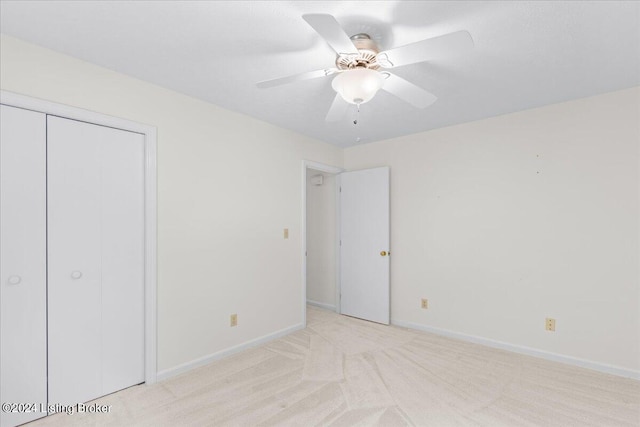 unfurnished bedroom with light colored carpet, a closet, and ceiling fan