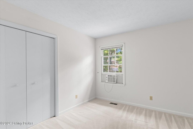 unfurnished bedroom with a closet, light carpet, and a textured ceiling