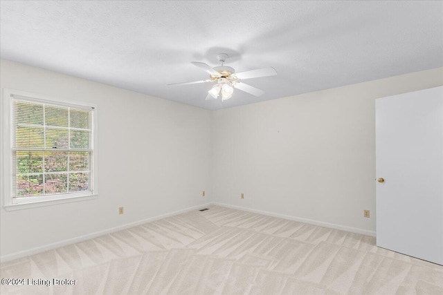 carpeted spare room featuring a textured ceiling and ceiling fan