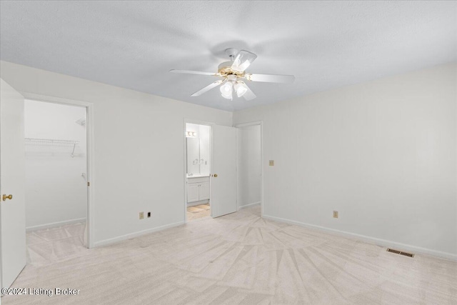 empty room with light carpet, a textured ceiling, and ceiling fan