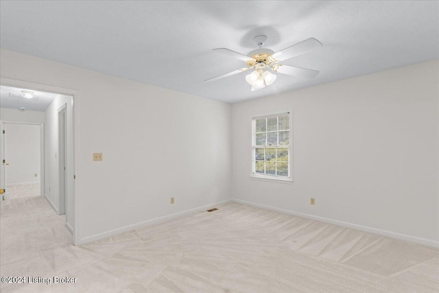 spare room featuring light colored carpet and ceiling fan