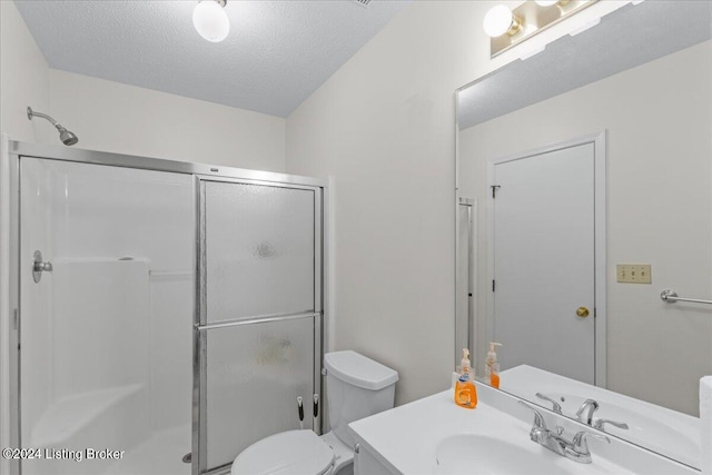 bathroom featuring vanity, a textured ceiling, toilet, and an enclosed shower