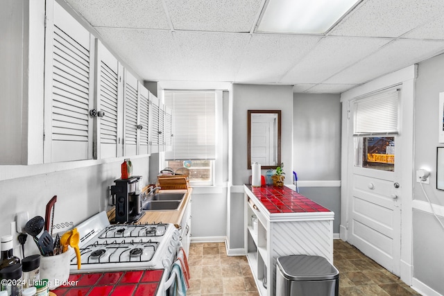 kitchen featuring sink, a paneled ceiling, and gas range gas stove