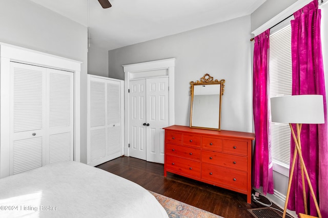 bedroom featuring dark wood-type flooring, two closets, and ceiling fan