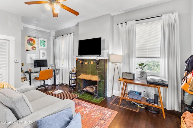 living room featuring ceiling fan, a fireplace, and dark hardwood / wood-style flooring