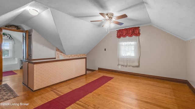 bonus room with lofted ceiling, a textured ceiling, wood-type flooring, and plenty of natural light