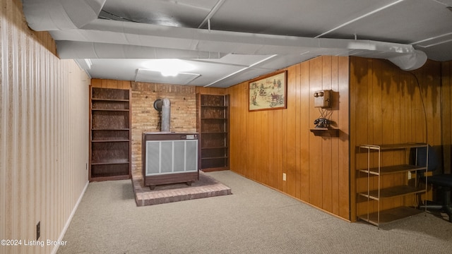 interior space featuring wooden walls, light carpet, built in shelves, and a wood stove