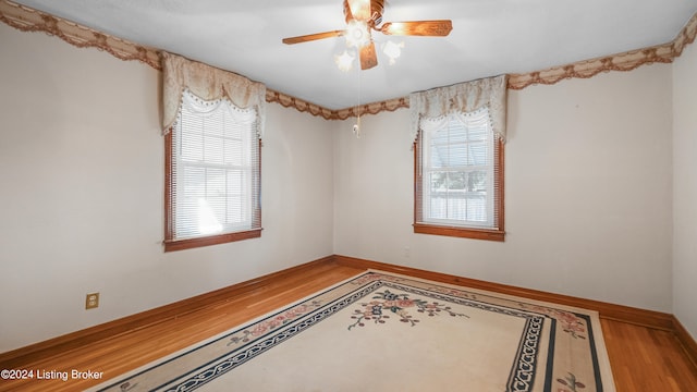 unfurnished room with a healthy amount of sunlight, hardwood / wood-style flooring, and ceiling fan