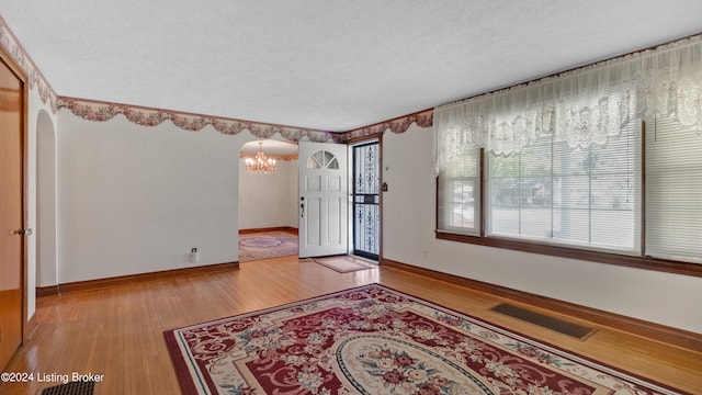 interior space with light hardwood / wood-style floors, a textured ceiling, and a chandelier