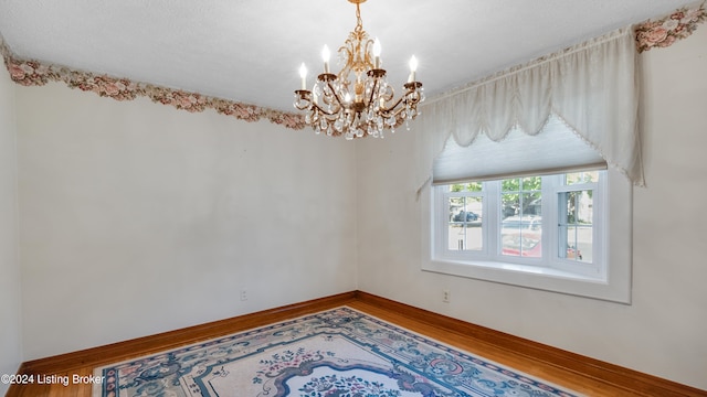 empty room with an inviting chandelier and hardwood / wood-style flooring