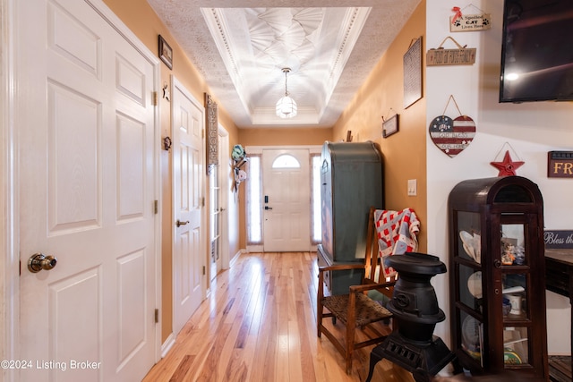 entrance foyer featuring a raised ceiling, a textured ceiling, ornamental molding, and light wood-type flooring