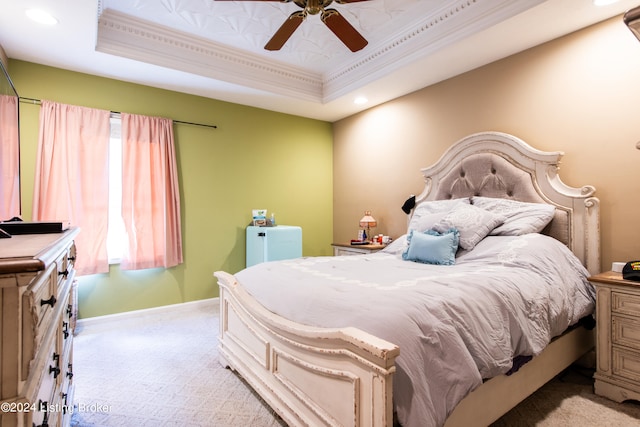 bedroom featuring ornamental molding, ceiling fan, light carpet, and a raised ceiling