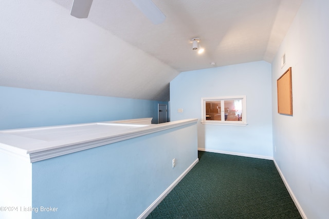 hallway with lofted ceiling and dark colored carpet