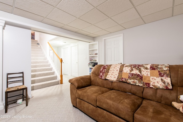 living room featuring carpet and a drop ceiling