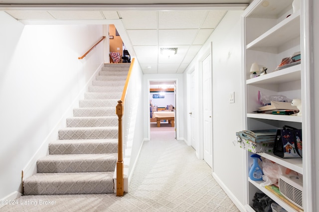 staircase with carpet and a paneled ceiling