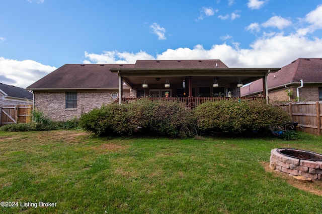 back of property featuring an outdoor fire pit and a lawn